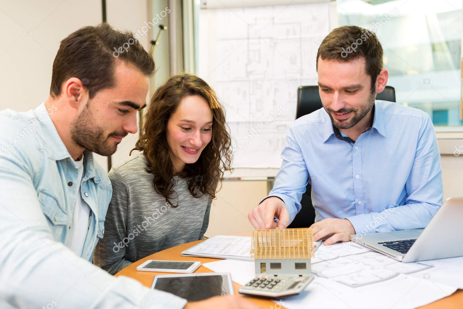 Young attractive couple signing contract with real estate agent